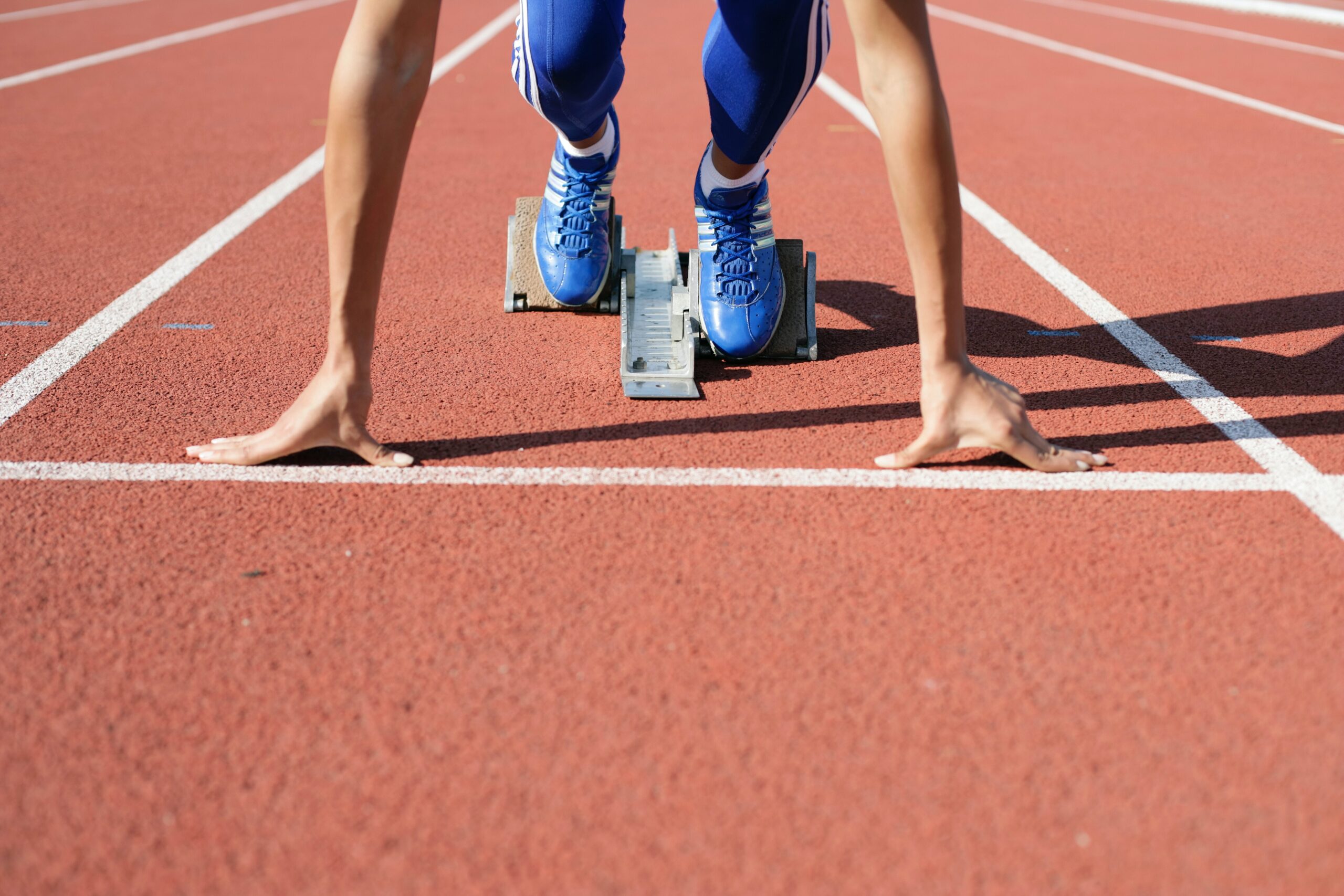 Female sprinter set to push off of a starting block on the track