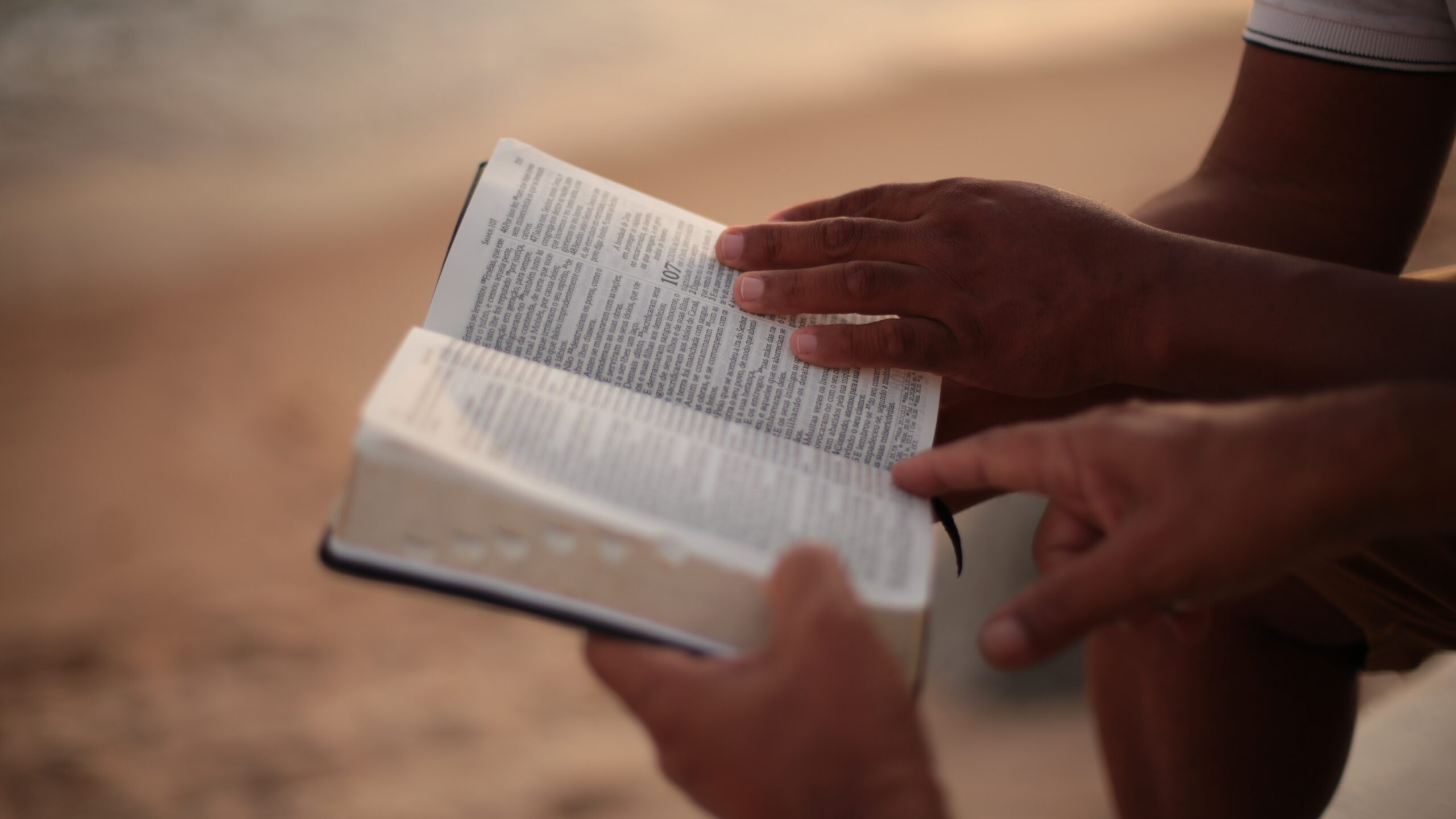 Photo of an open Bible held by two people's hands